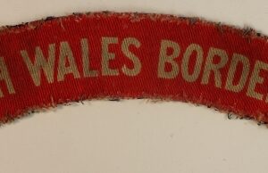 SOUTH WALES BORDERERS WW2 Printed Shoulder Title Badge - CALICO PRINTERS  ---  Lot No. 6759